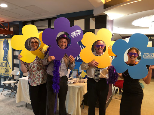 A cheerful group of individuals holding colorful flower-shaped props at an event.