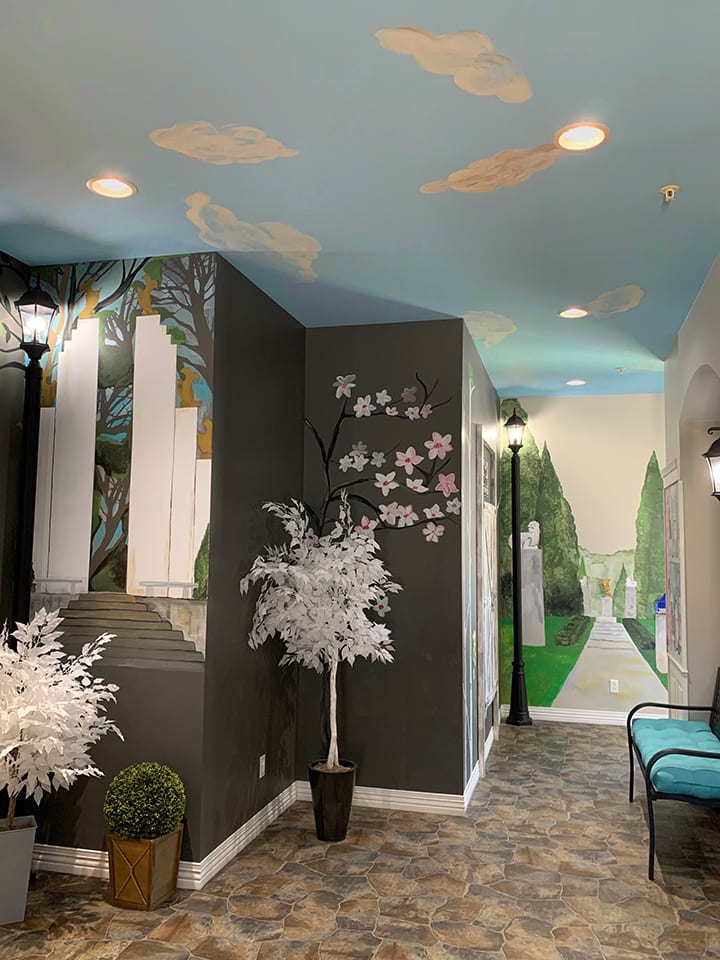 A creatively decorated hallway featuring murals, ceiling art, and decorative trees.