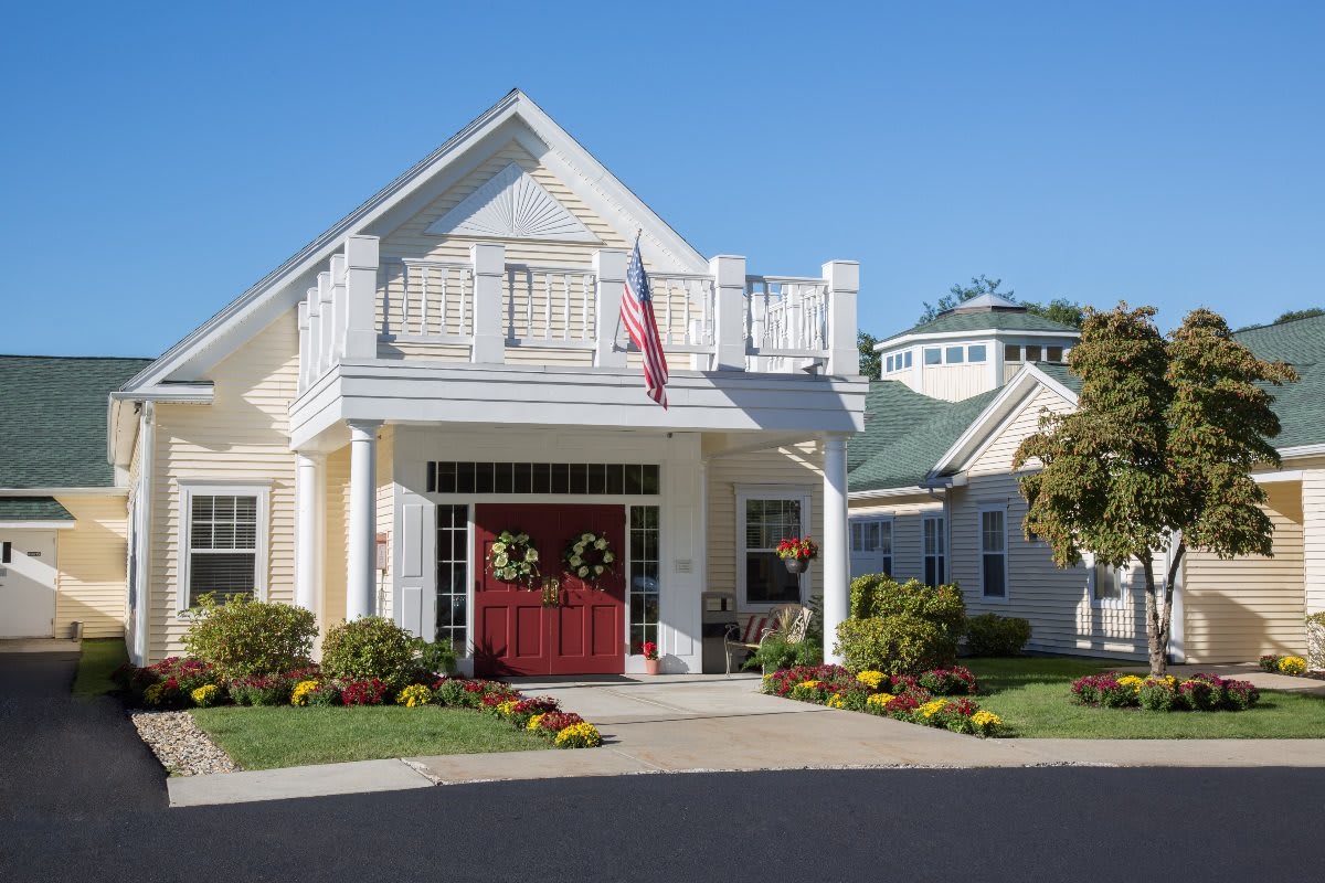 A well-maintained residential house with an American flag and attractive landscaping.