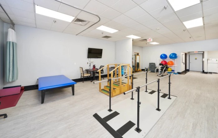 A physical therapy room equipped with parallel bars and exercise equipment.
