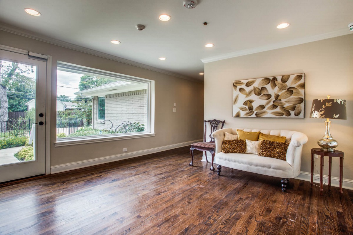 A modern living room featuring hardwood floors, a large window, and comfortable seating.