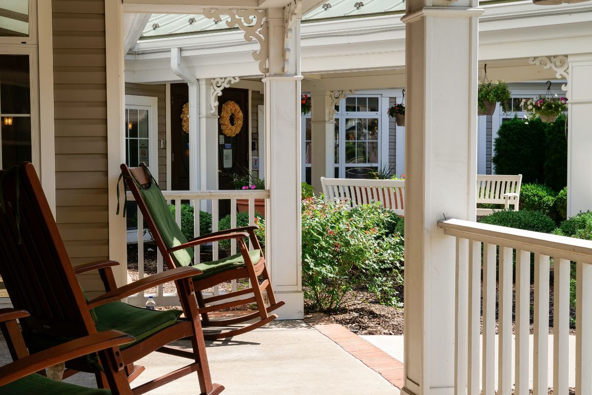A tranquil porch with rocking chairs and a view of the garden on a sunny day.
