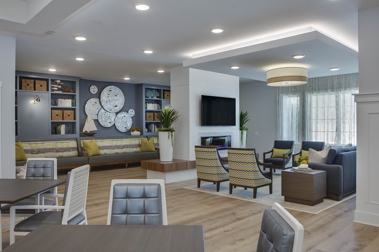 A modern living room with contemporary design featuring a seating area, decorative clocks, bookshelves, and a television.