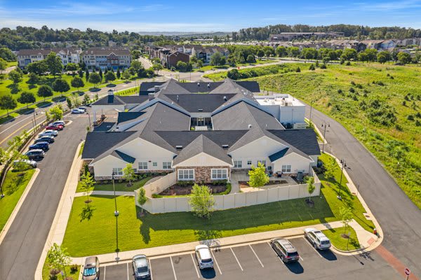 Aerial view of a large building with a surrounding parking lot and green landscape.