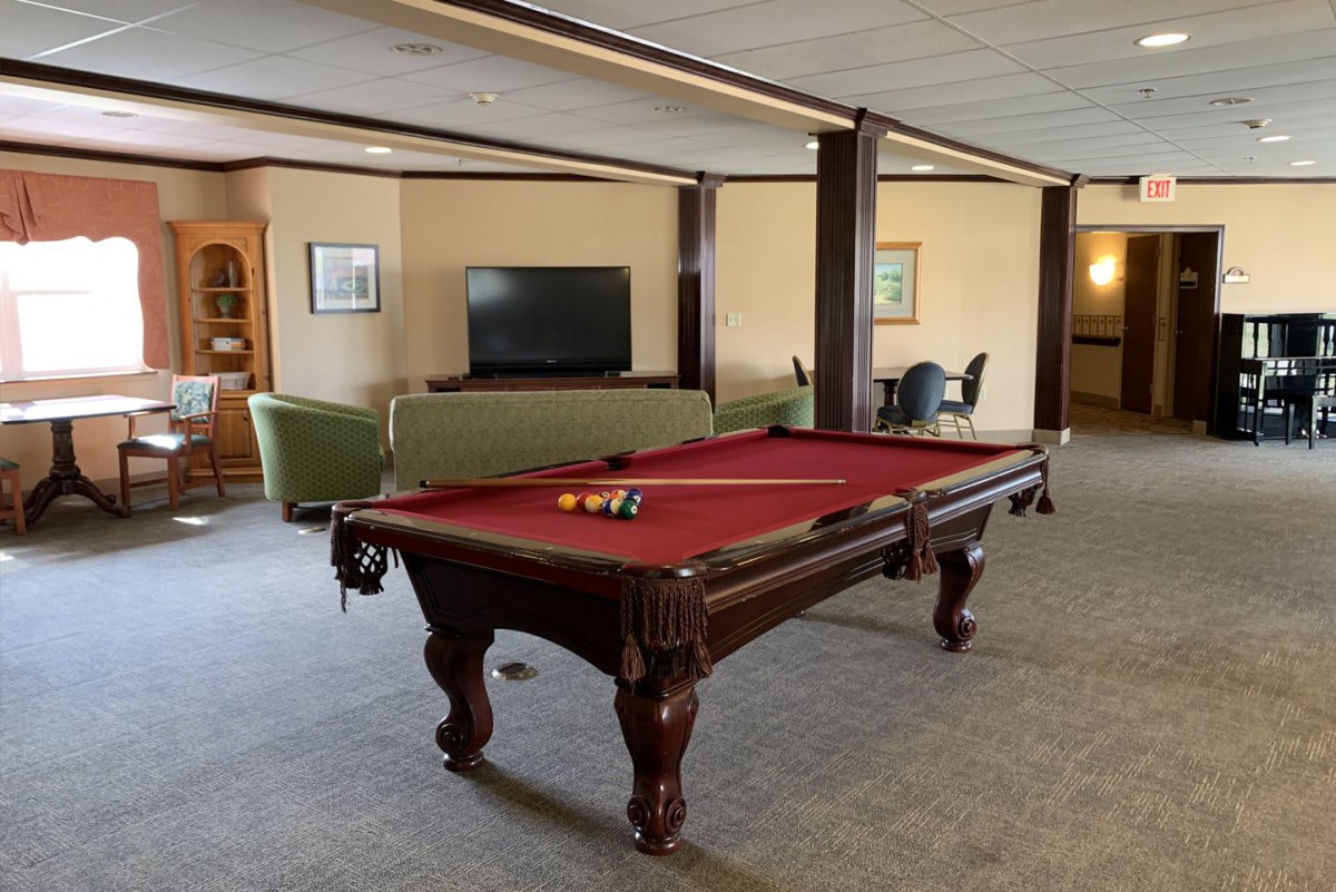 A spacious game room featuring a pool table and a cozy seating area with a television.
