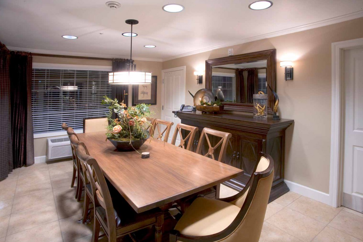 A well-decorated dining room featuring a long wooden table, elegant chairs, and ambient lighting.