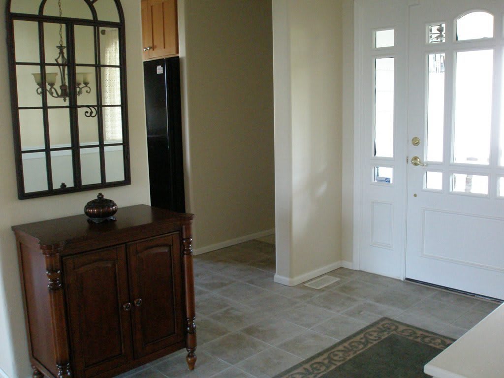 A well-lit entrance hall with a mirror and wooden cabinet.