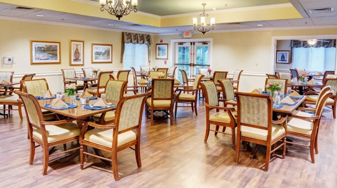 A well-lit dining room with wooden furniture and chandeliers.