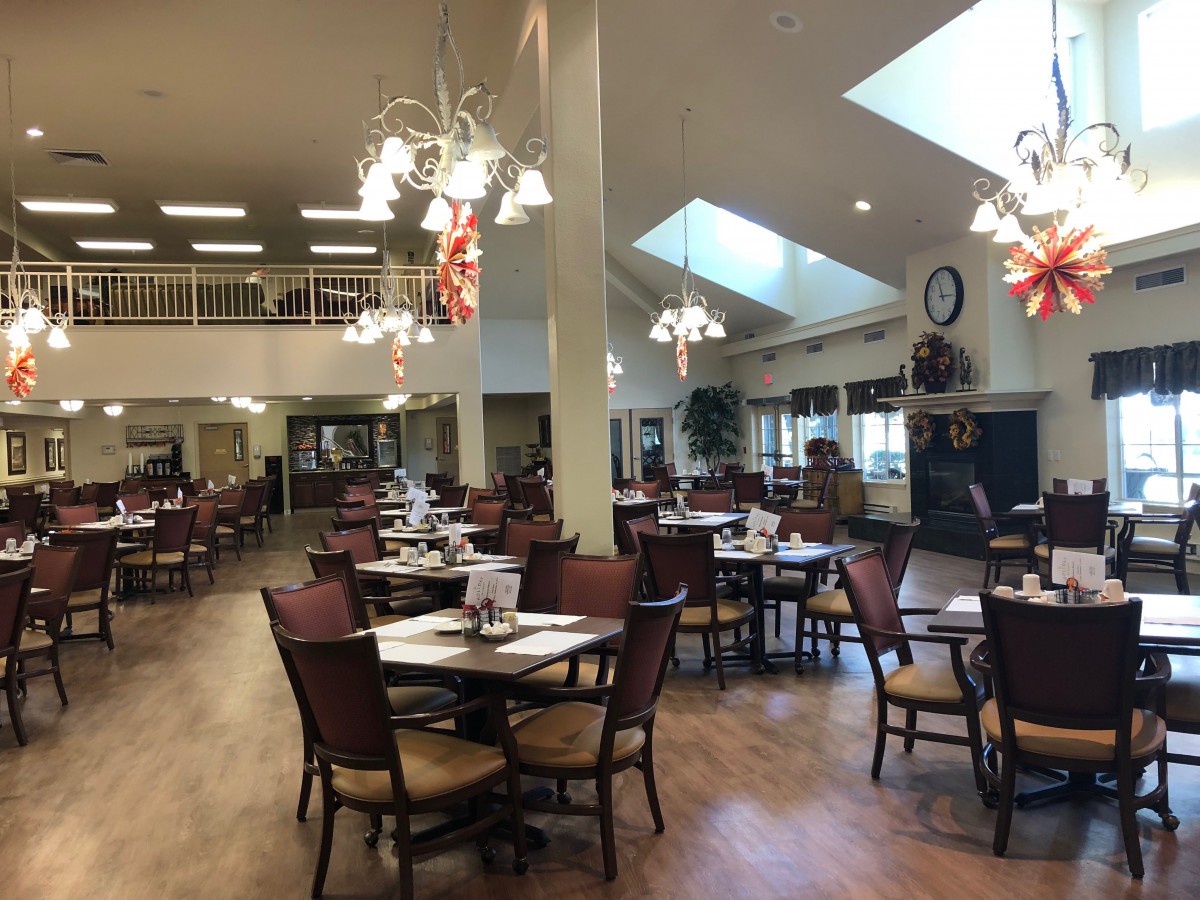 A spacious restaurant dining area with tables and chairs set up, featuring elegant lighting fixtures.