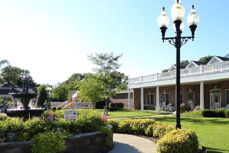 A serene garden area with a pathway and classic lamp posts alongside a building.