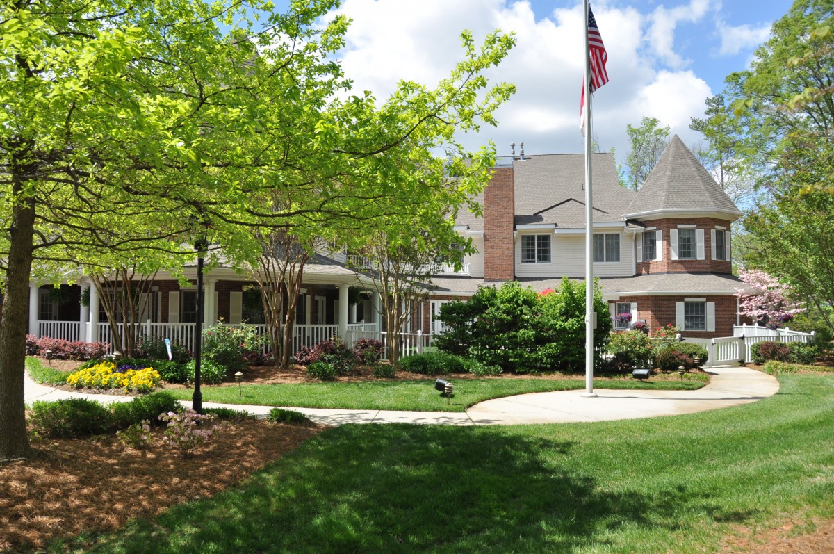 A peaceful building surrounded by a well-maintained garden and a flagpole on a sunny day.