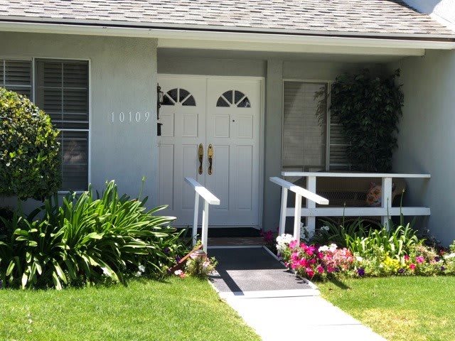 A welcoming house entrance with a garden and flowers.