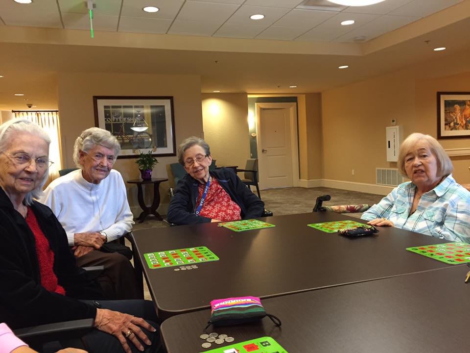 A group of seniors enjoying a social gathering around a table indoors.