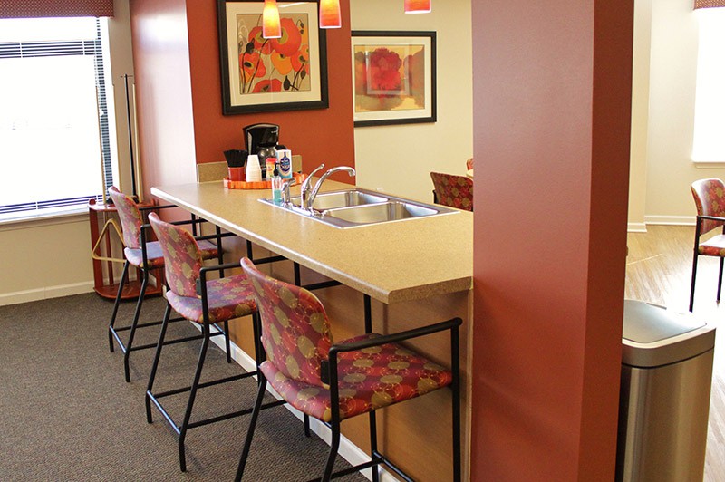 A cozy kitchen area with a long counter, bar stools, and warm pendant lighting.