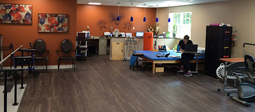 A spacious therapy room featuring workstations and a blue treatment table, designed for rehabilitation.