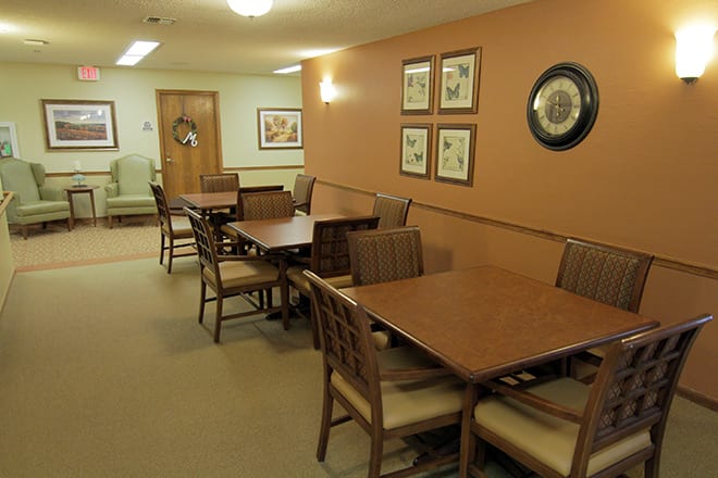 A cozy dining area with wooden tables and chairs, decorated with wall art and soft lighting.