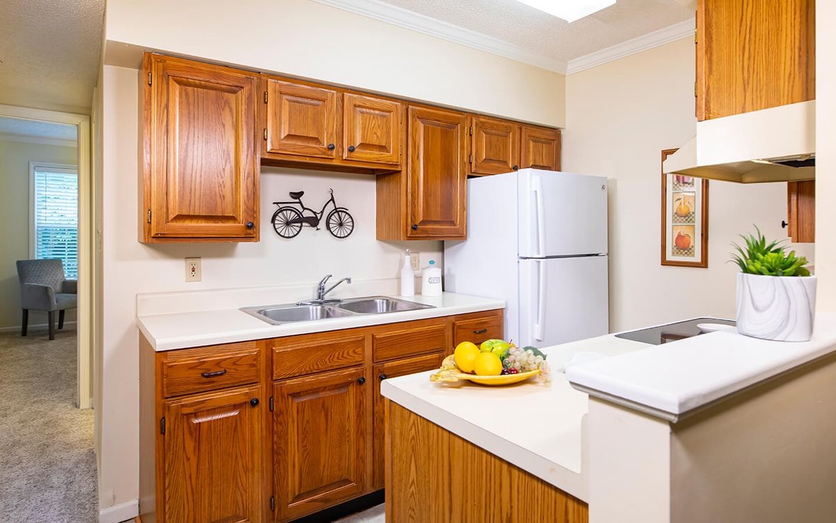 A cozy kitchen featuring wooden cabinets, a white refrigerator, and a countertop with a fruit basket.