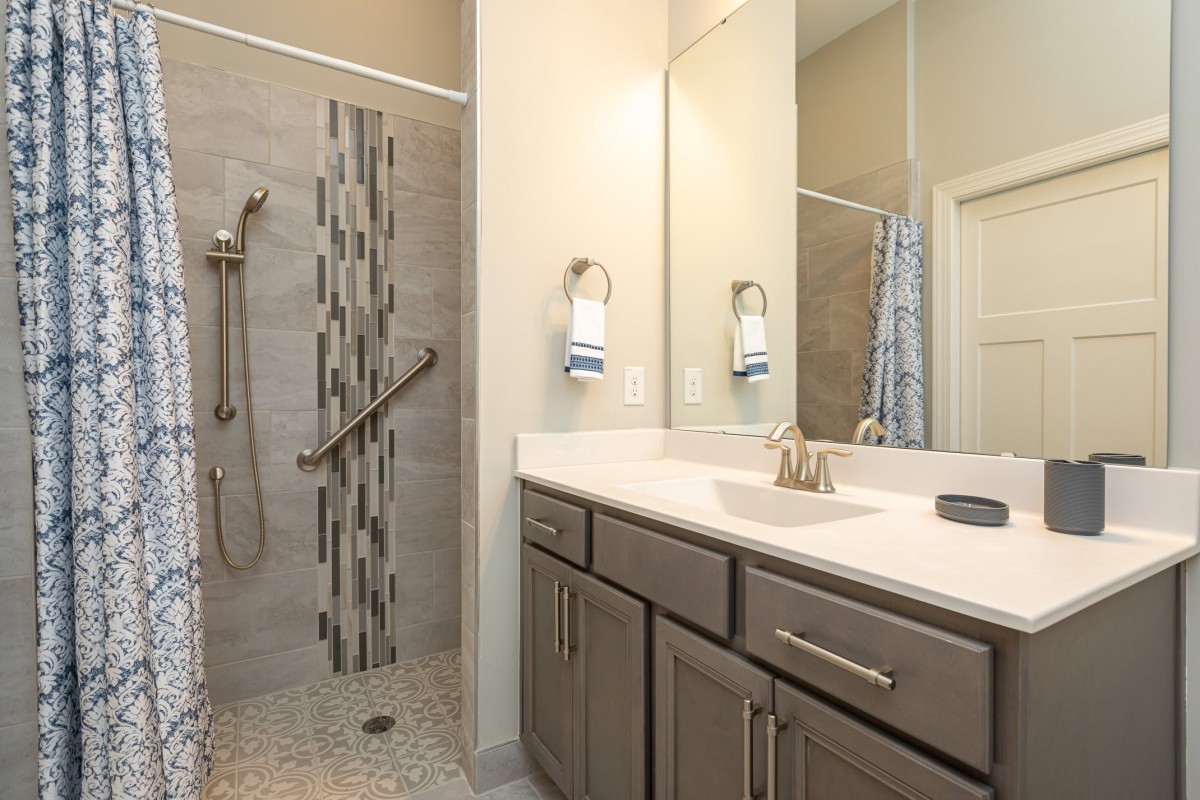 A modern bathroom with a sleek vanity, large mirror, and a walk-in shower.
