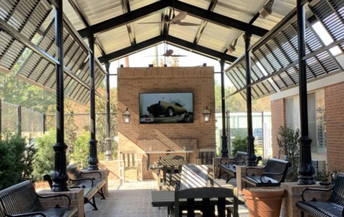 A cozy outdoor patio with comfortable seating and a television mounted on a brick wall.