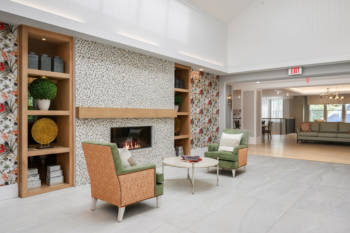 A modern living room with a fireplace, featuring green chairs and minimalist decor.