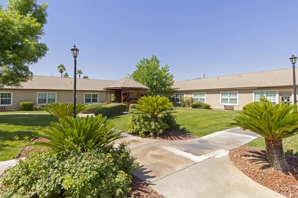 A scenic view of a landscaped garden with a pathway leading to a building on a sunny day.