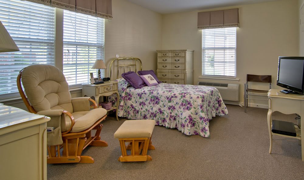 A cozy bedroom with floral bedding and a wooden rocking chair.