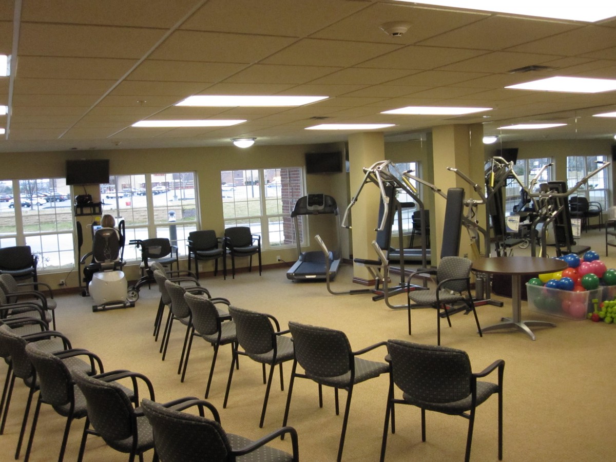 A fitness center with exercise equipment and chairs arranged for a meeting.