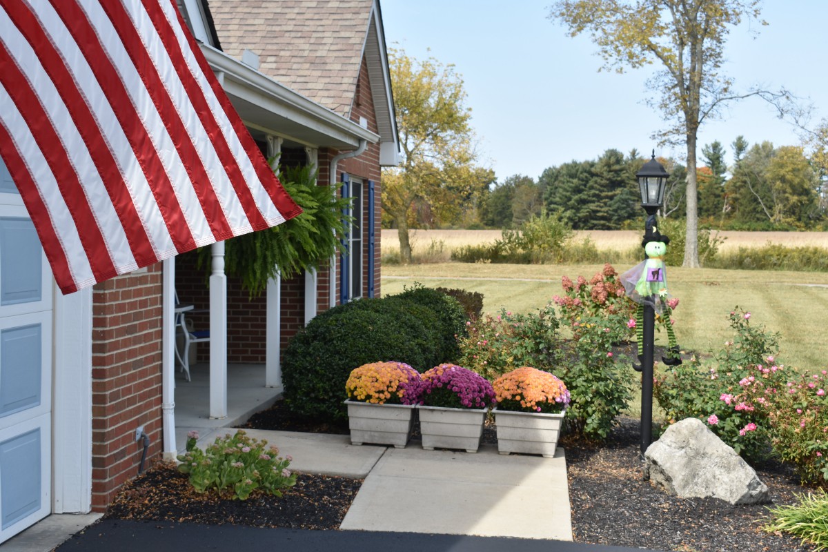 A charming house entrance with an American flag and colorful flowers in planters.