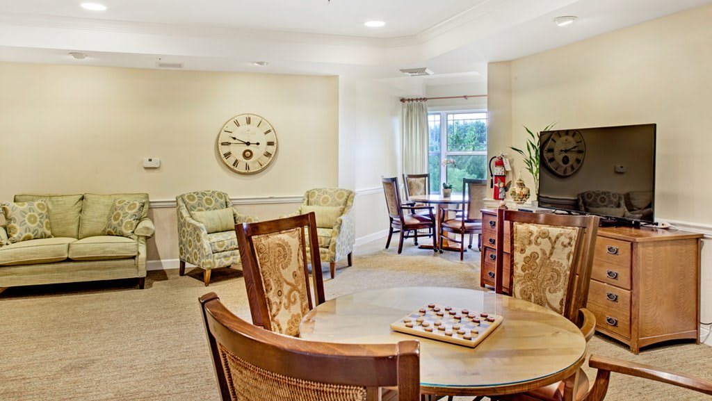 A cozy living room with a table, chairs, and a wall clock.