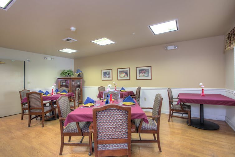 A well-arranged dining room with tables set for a meal, featuring elegant decor and framed artwork on the walls.