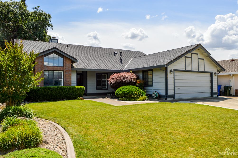 A charming single-story house with a well-maintained lawn and front yard on a sunny day.