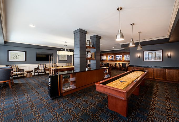 A modern game room with a shuffleboard table and comfortable seating.