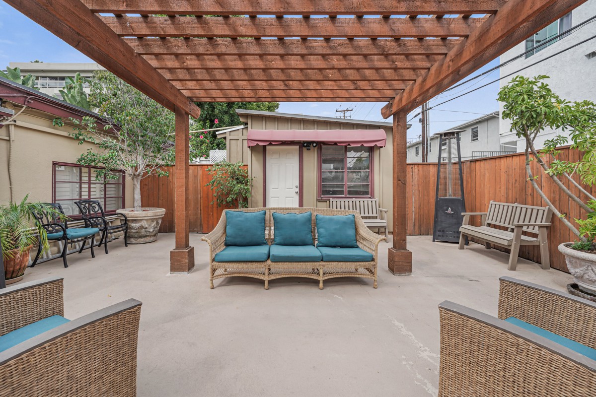 A cozy outdoor patio with a wooden pergola and cushioned seating.