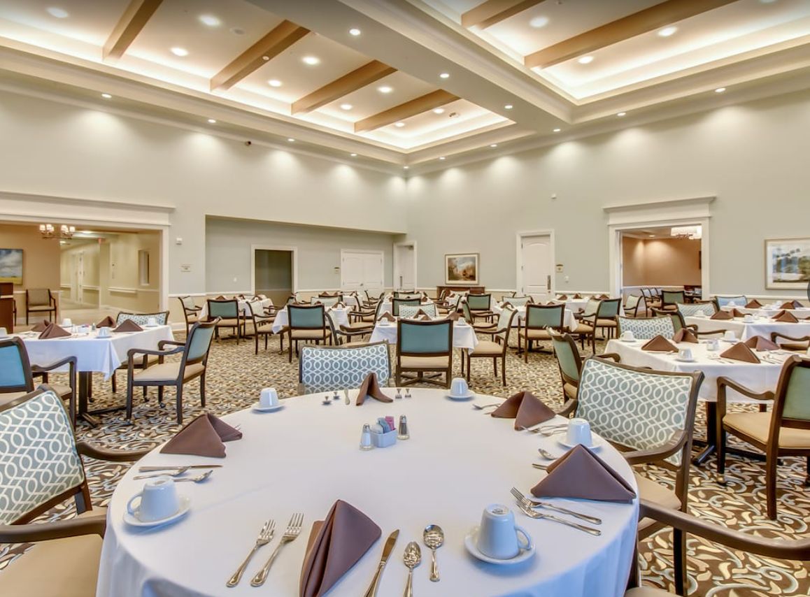 An elegant dining room setup with round tables and white tablecloths, ready for guests.