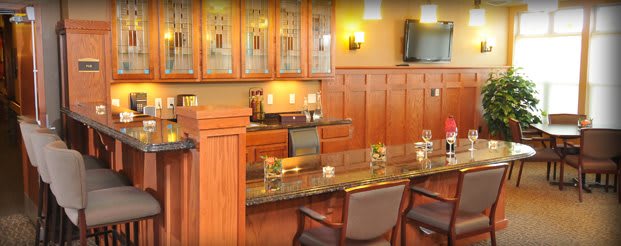 A cozy bar area with wood paneling, a sleek countertop, and comfortable seating.