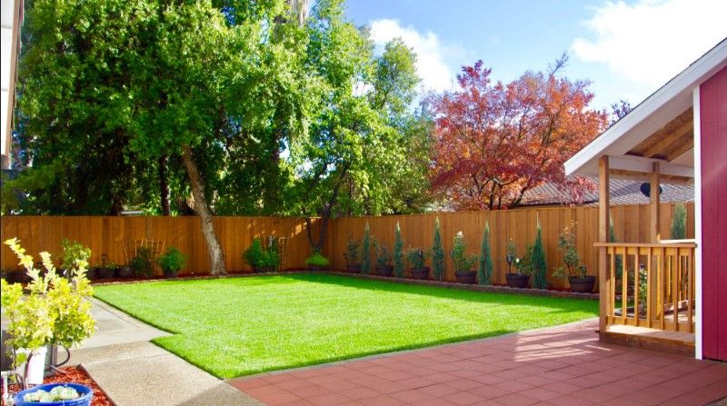 A neatly landscaped backyard with a lawn and surrounding trees.