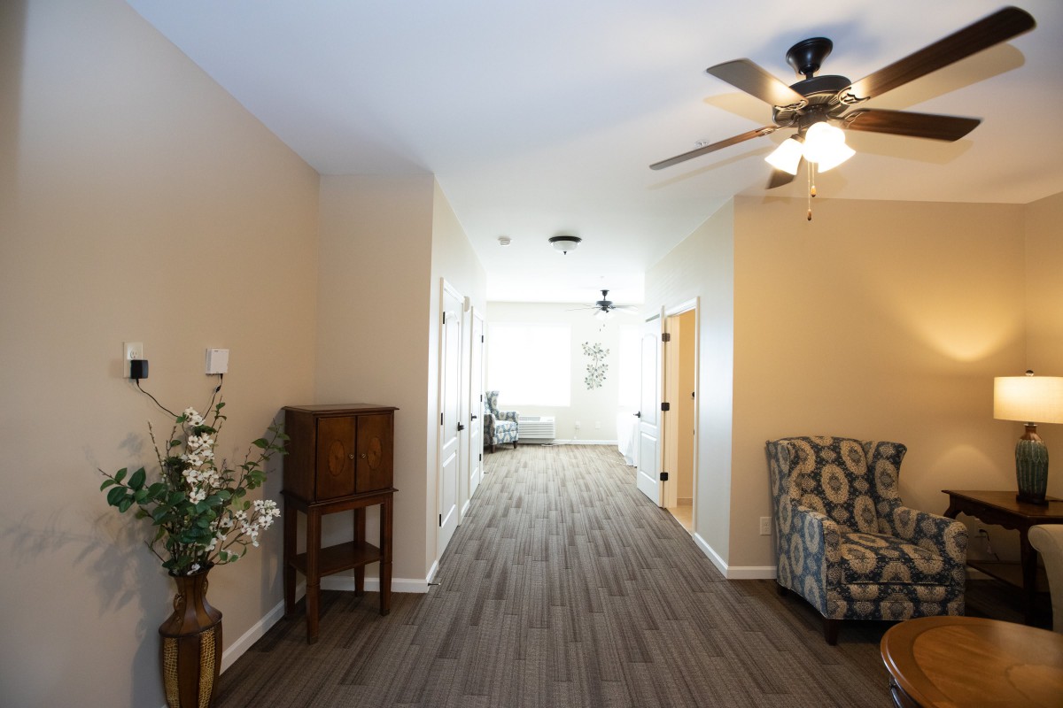 A well-lit hallway with wooden flooring and tasteful furniture.
