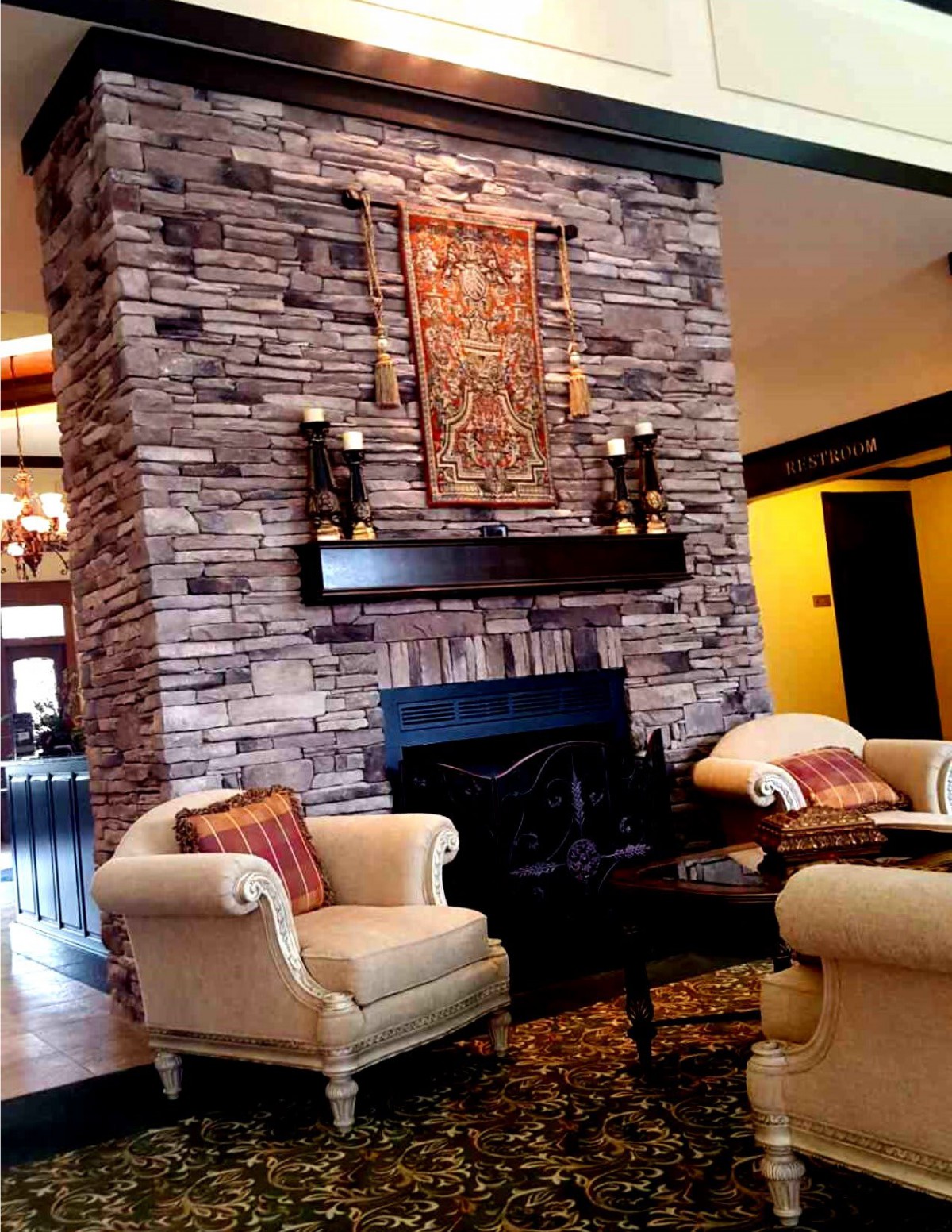 A cozy living room with a stone fireplace and elegant armchairs.