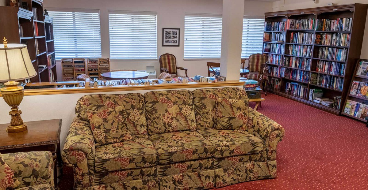 A cozy living room with a floral-patterned sofa, bookshelves, and seating area.