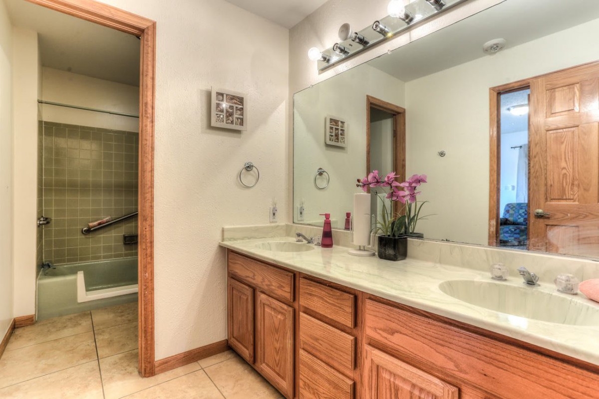 A clean and well-organized bathroom with a double sink vanity and wooden cabinets.