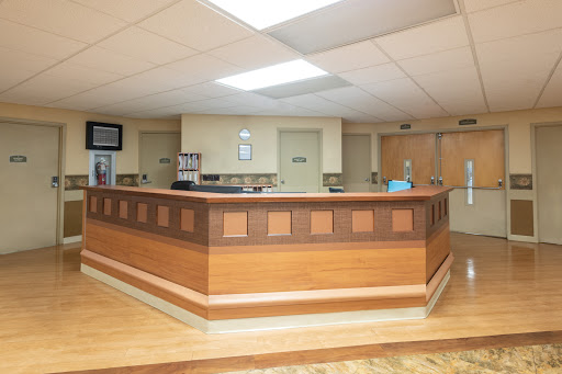 A modern hospital reception area featuring a wooden desk and bright lighting.