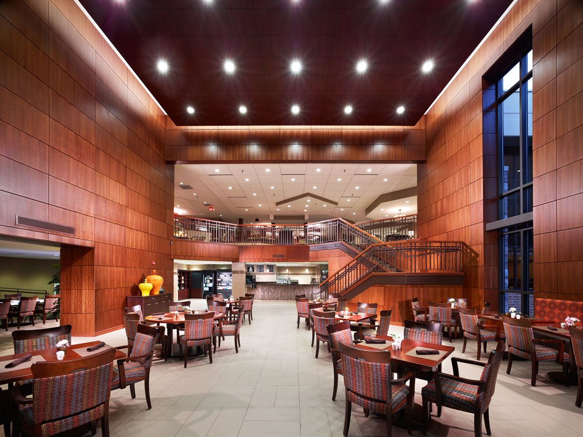 A modern restaurant interior features wood paneling, ample seating, and elegant lighting.