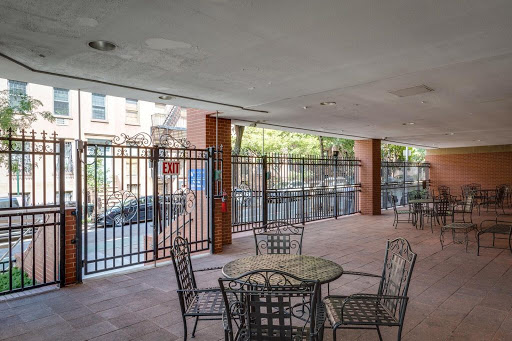 An inviting outdoor seating area with tables and chairs, enclosed by a fence in an urban setting.