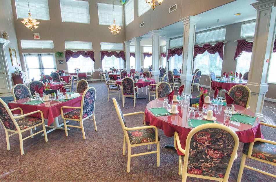 A spacious dining area with elegantly set tables and chairs, featuring large windows and decorative interior elements.