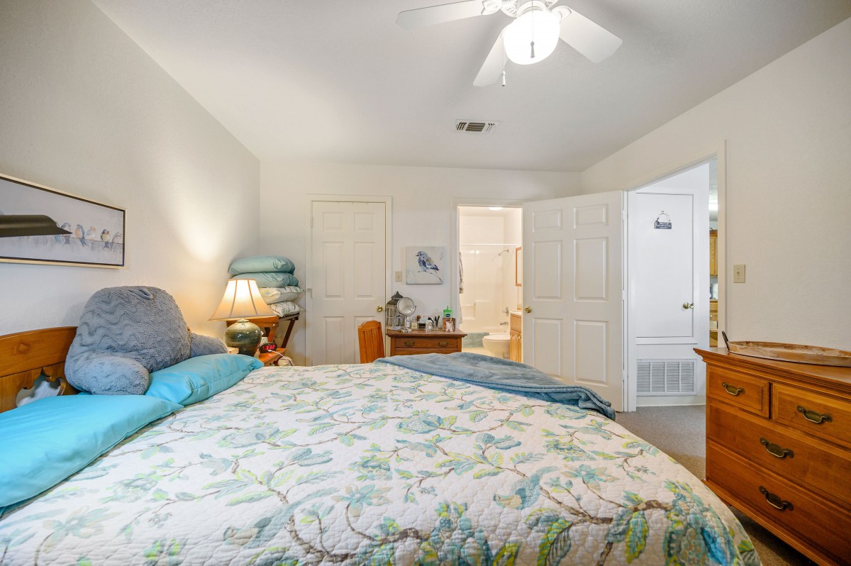 A cozy bedroom with a large bed, soft bedding, and warm lighting from a bedside lamp.