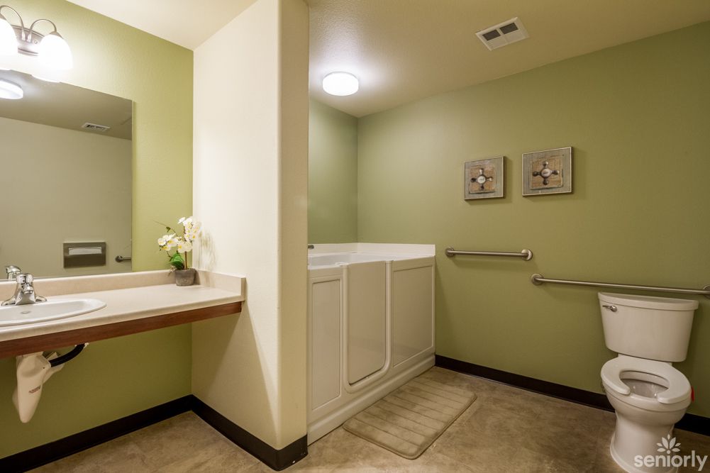 A modern bathroom interior with green walls, featuring a sink with a mirror and cabinetry.