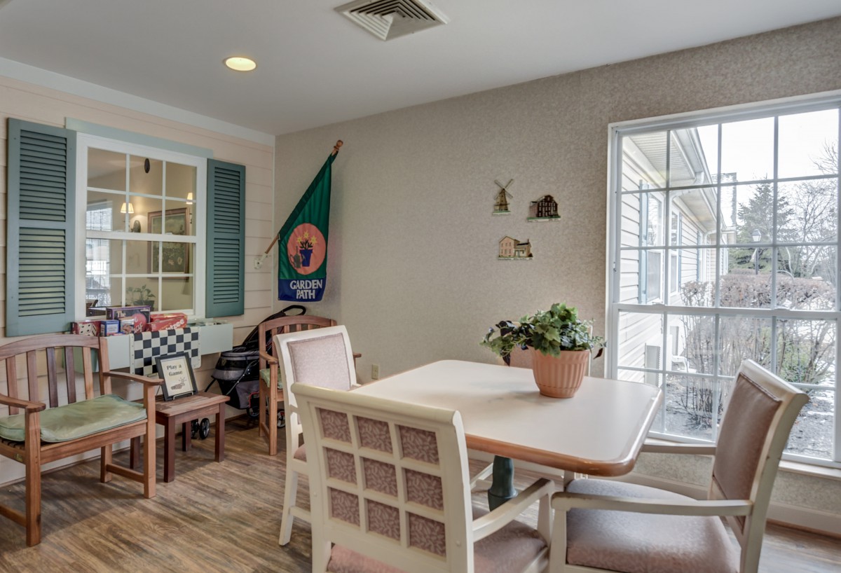 A cozy dining area with a table and chairs, adorned with an indoor plant and illuminated by natural light from a nearby window.