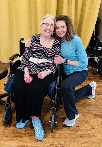 A joyful moment shared between a caregiver and an elderly individual during a wellness activity.