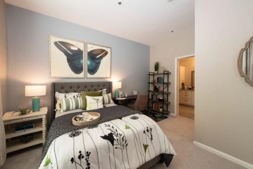 A modern bedroom with stylish decor and artwork above the bed.