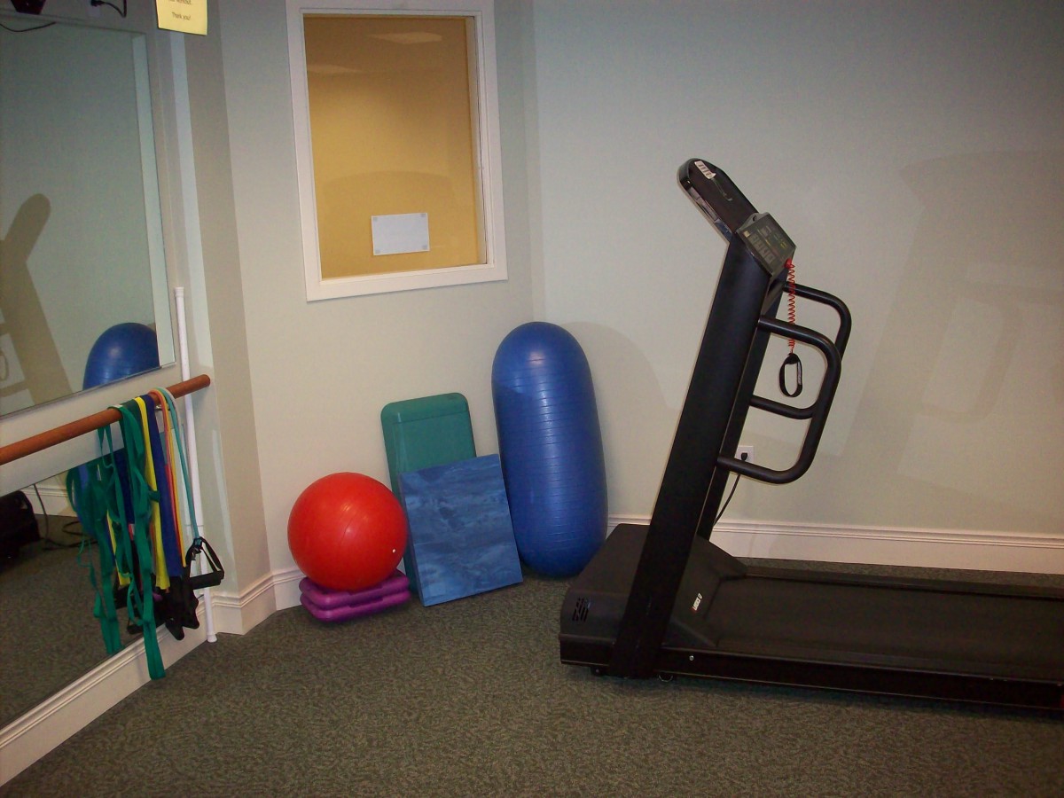A small gym area featuring a treadmill, exercise balls, and yoga mats.